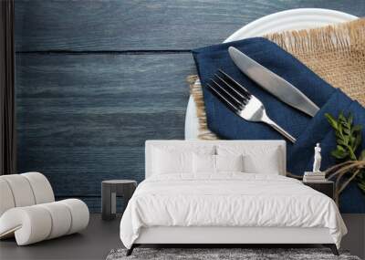 Table setting. plate and cutlery in a blue napkin, fork and knife on a blue wooden table. top view Wall mural