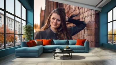 Young attractive girl in a coat in the city at sunset Wall mural