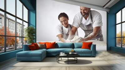 A happy young couple is having fun kneading dough in the kitchen.  Wall mural