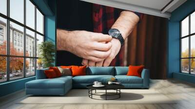 close up fashion details, young fashionable man wearing a red checked shirt and a black analog wrist watch. street style detail of an elegant clock. Wall mural