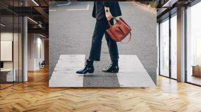 fashion blogger autumn 2019 outfit details. fashionable woman wearing black jeans, black ankle shoes a brown tan trendy leather handbag. crossing the street. detail of a perfect fall fashion outfit.  Wall mural