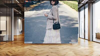 fashion blogger street style. fashionable woman posing wearing an oversized blazer, floral vintage dress, black ankle boots and a black trendy mini handbag. detail of a perfect fall 2019 outfit.  Wall mural