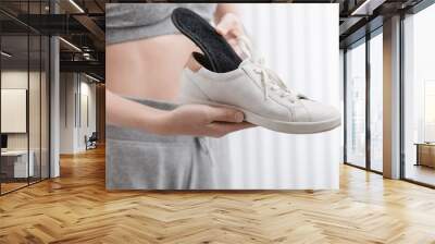 woman putting orthopedic insole into shoe at home. sports girl fitting orthopedic insole indoors, cl Wall mural