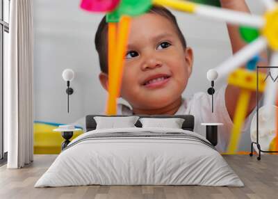 A cute boy playing with preschool math manipulative toys and with a facial expression that shows wonder or thinking. Wall mural