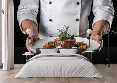 A chef presents a gourmet dish featuring a beautifully cooked steak accompanied by fresh vegetables and herbs. Wall mural