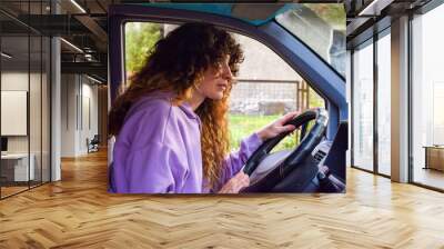 Independent curly hair backpacker woman driving scared lost during an adventure road trip with her camper van Wall mural