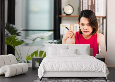 A middle-aged Asian woman work at home office check information online using laptop Wall mural