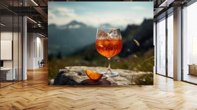 A glass with an Aperol Spritz cocktail against the backdrop of snow-capped mountains. Generative AI. Wall mural