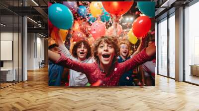 A group of cheerful eleven years old friends celebrating birthday indoors with colorful confetti and balloons. Crazy preteen birthday party at home. Wall mural