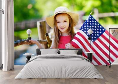 Adorable little girl holding american flag outdoors on beautiful summer day Wall mural