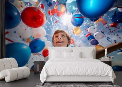 Cheerful funny child holding colourful balloons on a sky background. Kid having fun with balloons and confetti. Wall mural