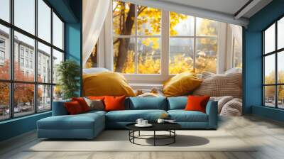 Cozy reading nook with white and yellow pillows, a blanket, a white framed window looking out to a beautiful garden in autumn, with natural light streaming through the windows. Wall mural