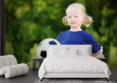 Cute little soccer player having fun playing a soccer game on summer day Wall mural