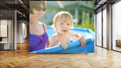 Cute teenage sister and her toddler brother having fun in outdoor pool. Child learning to swim. Kid having fun with water toys. Family fun in a pool. Wall mural