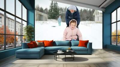 Funny young girl and her grandma having fun with a sleigh in beautiful winter park. Cute child playing in a snow. Wall mural