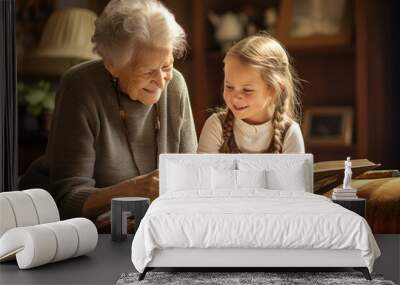 Grandmother and granddaughter watching old photo album at home. Senior woman showing to child black and white retro photos. Retired person and kid happy together. Wall mural