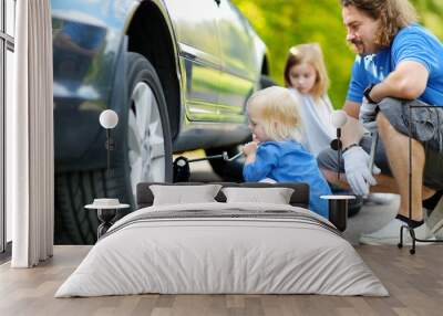 Little girl helping father to change a car wheel Wall mural