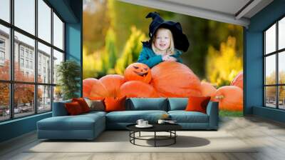 Little girl wearing halloween costume on a pumpkin patch Wall mural