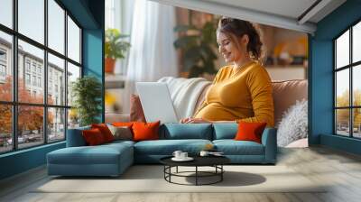 Pregnant woman using her laptop computer at home, browsing or chatting with friends online, online shopping for her baby. Wall mural