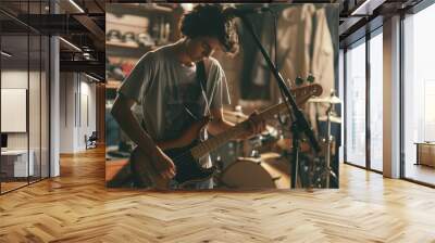 Teenage band practicing in a cramped garage, with cluttered equipment and members tuning instruments, immersed in their music preparation. Wall mural