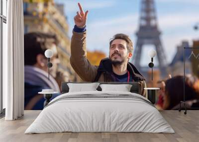 Tour guide leading a group of visitors to tourist attractions, giving them information and insights, pointing at local architecture in Paris, France. Wall mural