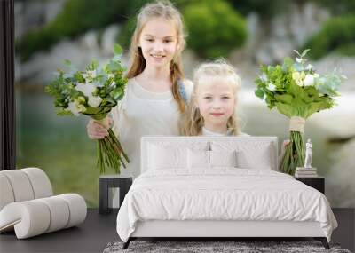 Two adorable young bridesmaids holding beautiful flower bouquets after wedding cemerony outdoors. Wall mural