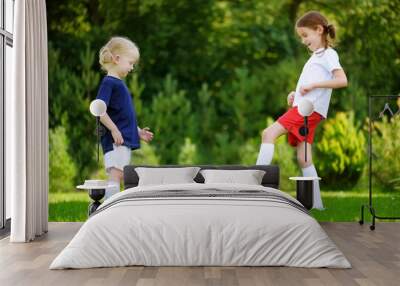 Two cute little sisters having fun playing a soccer game Wall mural