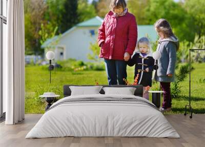 Two cute little sisters helping their grandmother in a garden. Children taking part in outdoor household chores. Wall mural