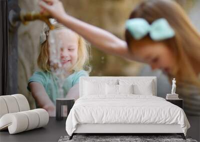 Two girls playing with drinking water fountain Wall mural