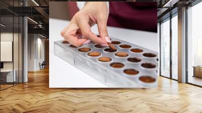 top view of confectioner adding almonds into caramel filling chocolate mold. chocolatier preparing luxurious handmade Belgian candy. preparation of premium handmade candies, truffles, chocolates Wall mural