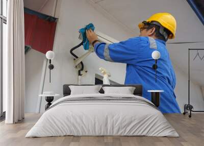 A male worker doing a maintenance work by cleaning and inspecting security camera. Wall mural