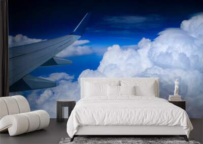 wing of an airplane flying above clouds Wall mural