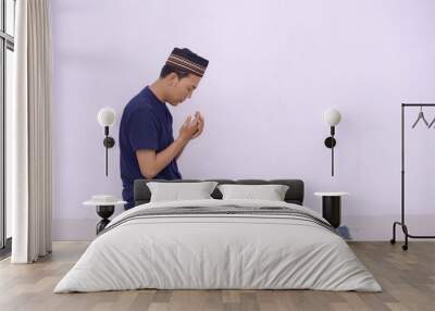 young asian muslim praying to the God isolated white background Wall mural