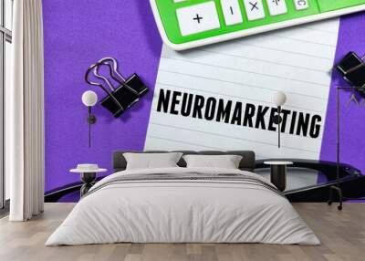 Business concept.Text NEUROMARKETING writing on notepaper with calculator,paper clips and glasseson purple background. Wall mural