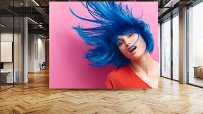 studio portrait of a sexy beautiful girl with a smile in motion on a pink background. Girl with blue hair Wall mural