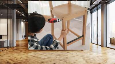 Asian woman assembles furniture by herself at home Wall mural