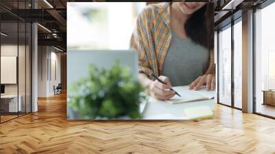 Young woman student busy study make notes in notebook and using laptop concentrated online training course technology education. Wall mural