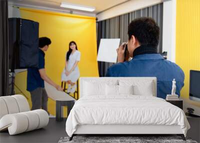 Behind the scenes, photographers are using cameras and lenses to shooting pictures of beautiful young women models smiling and posing in the studio with the backdrop and studio lights. Selective focus Wall mural