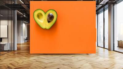 Heart-shaped avocado on orange background Wall mural