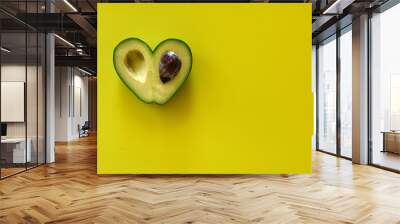 Heart-shaped avocado on yellow background Wall mural