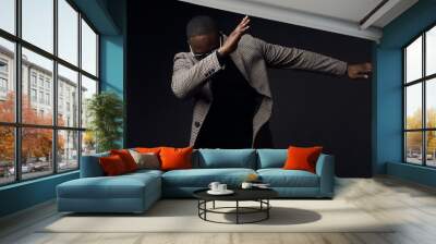 Serious cool man in black sweater and brown plaid coat and jeans. Studio, dark key Wall mural