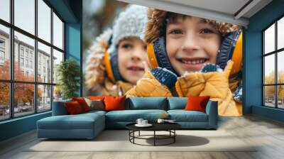 Joyful children in colorful quilted jackets and fluffy ear muffs, snowflakes clinging to their attire, embodying the spirit of winter fun and laughter. Wall mural