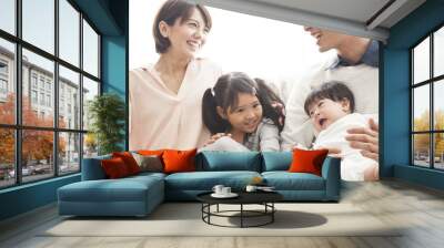 Parents, daughter and baby are sitting on the sofa and talking. Wall mural