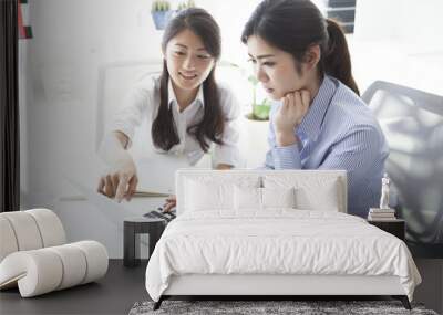 Two business women looking at a laptop together Wall mural