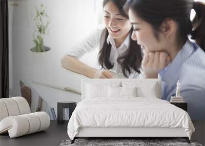 Two business women looking at a laptop together Wall mural