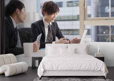 Two young businessman, looking at a laptop in the office Wall mural