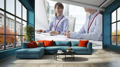 Two young women are working happily Wall mural