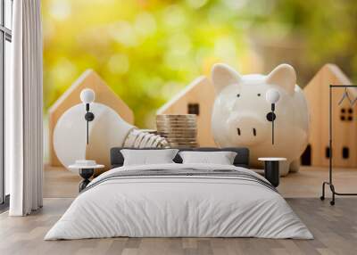 Energy saving and money concept, Piggy bank with light bulb and stack of coins for new house in the future on wooden table with green bokeh background. Wall mural