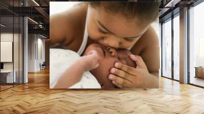 african american sister child kissing her newborn baby brother with love Wall mural