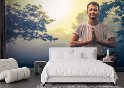 Asian male having Yoga excercise with background of sunshine over misty forest Wall mural